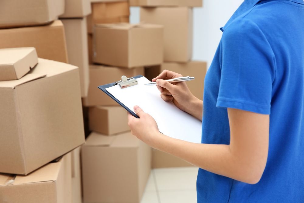 A Man is Writing on a Clipboard in Front of a Packages — Express Couriers Mackay in Moranbah, QLD