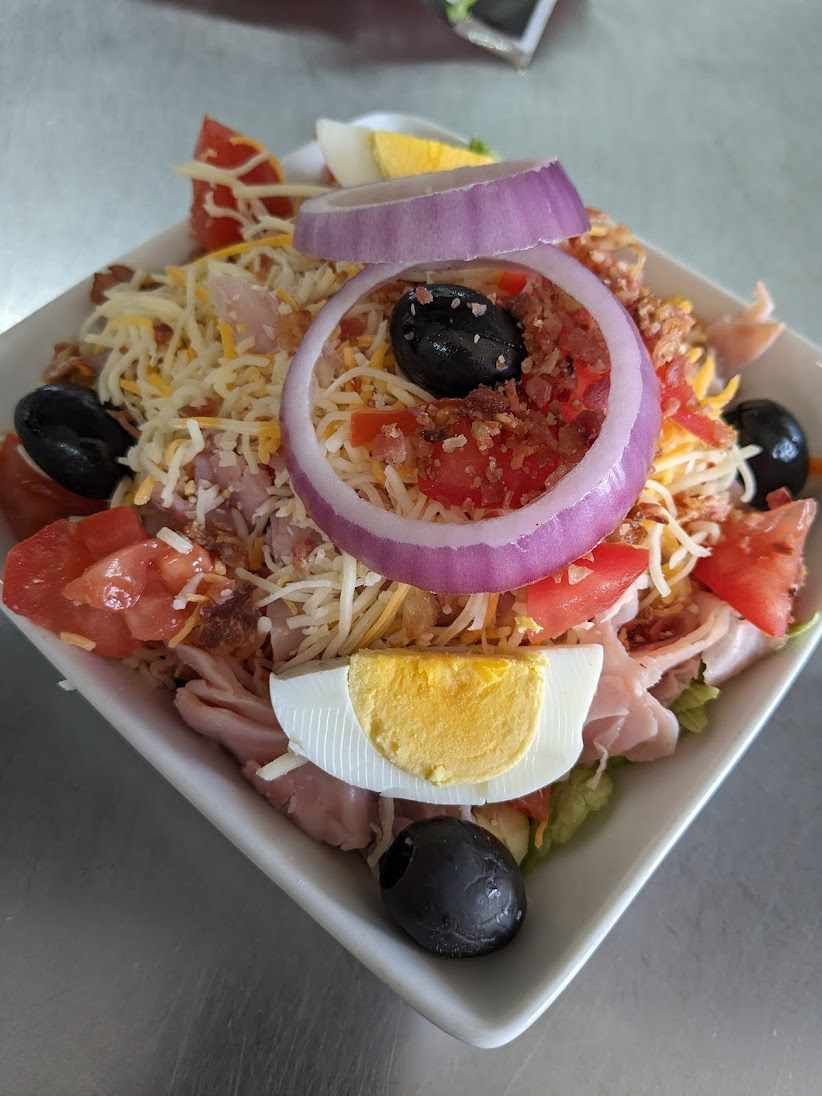 A salad with eggs , onions , tomatoes and olives on a plate