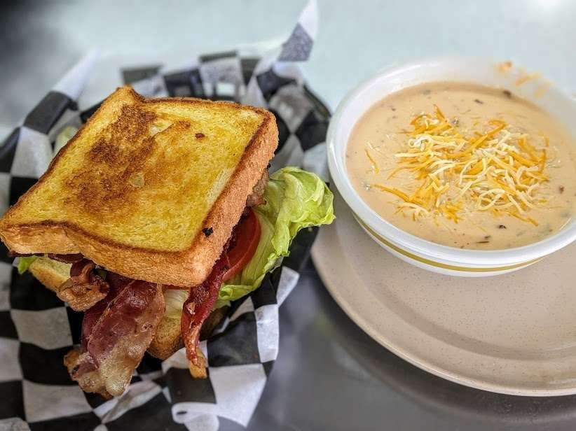 A sandwich and a bowl of soup are on a plate.