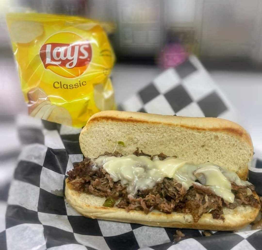 A sandwich with a bag of lays chips in the background
