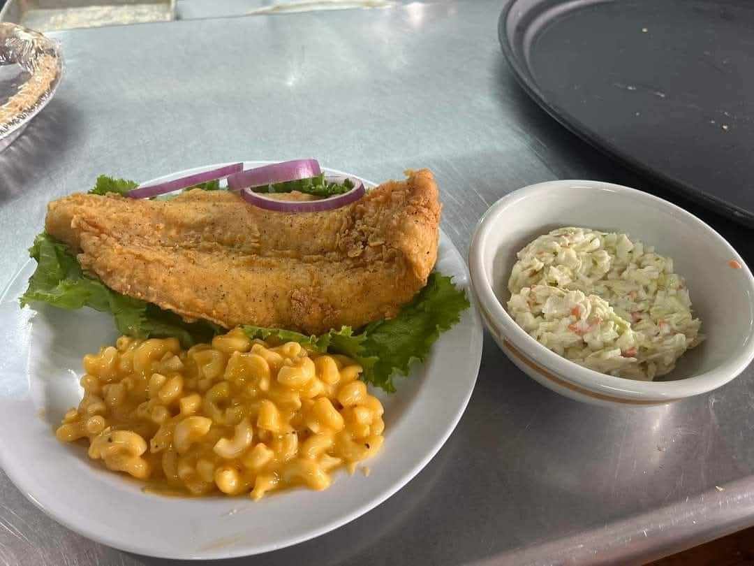 A plate of food with macaroni and cheese and coleslaw on a table.