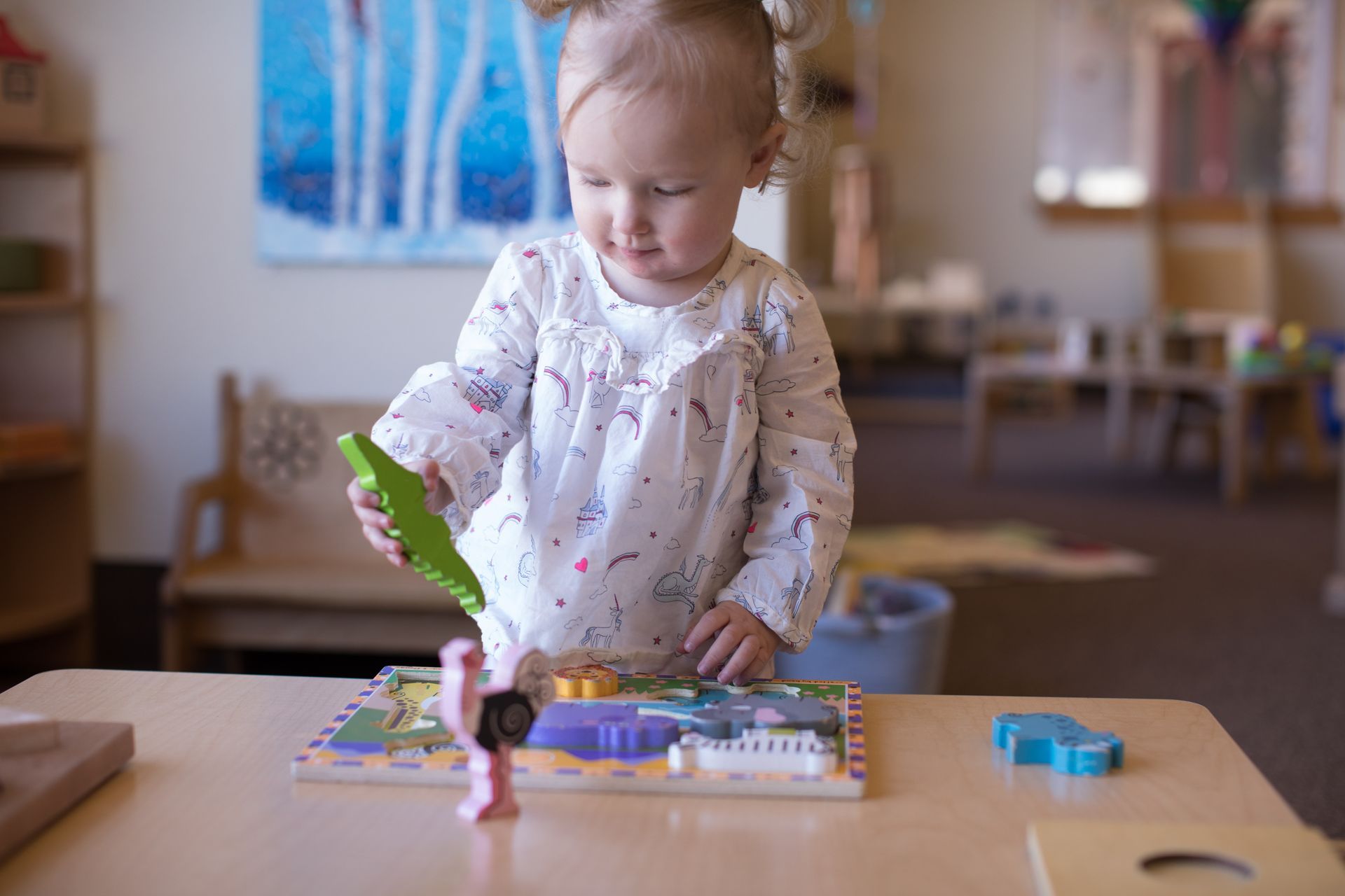 a little girl is playing with a wooden puzzle on a table .
