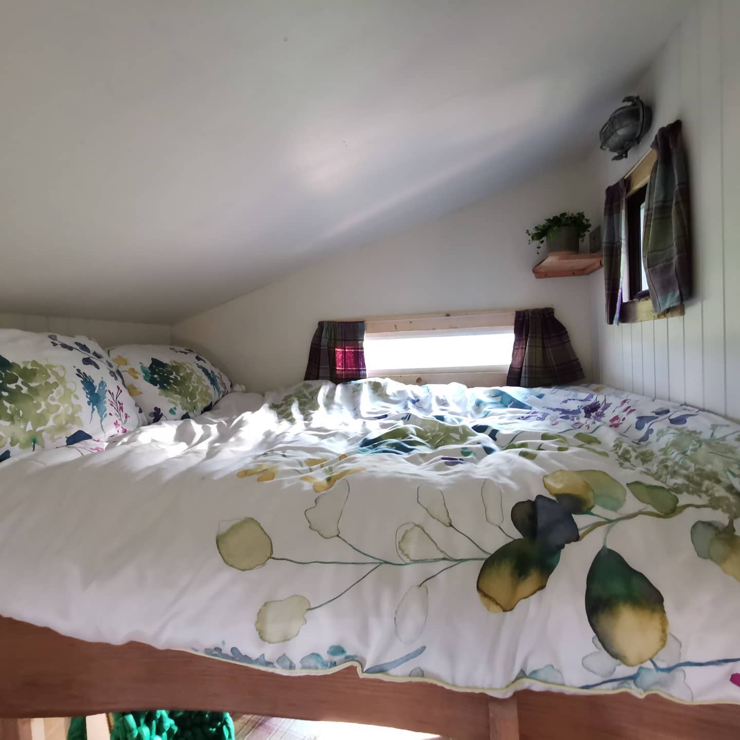 A bed with a floral comforter in a small room