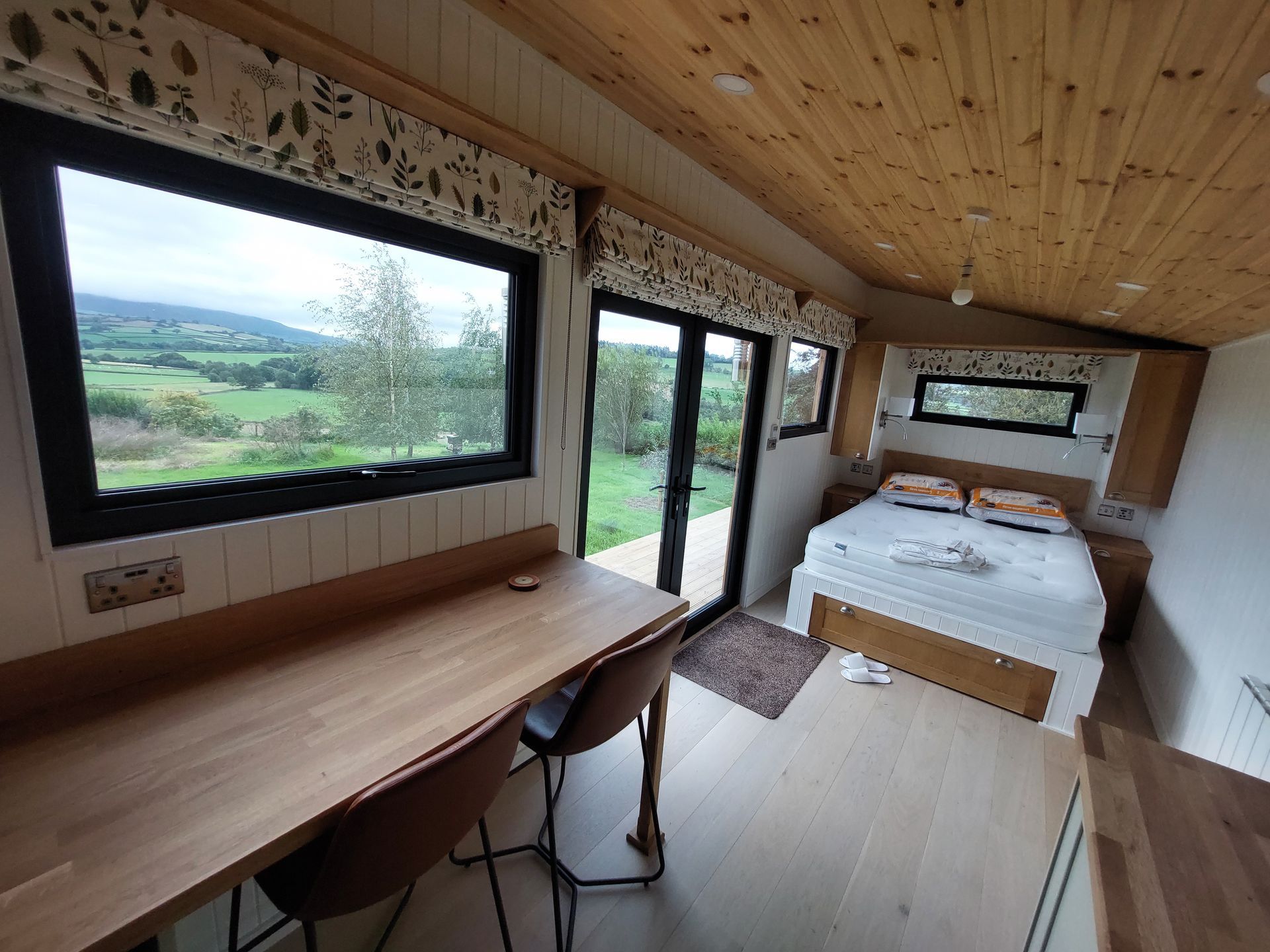 A bedroom with a bed , desk , chairs and sliding glass doors.