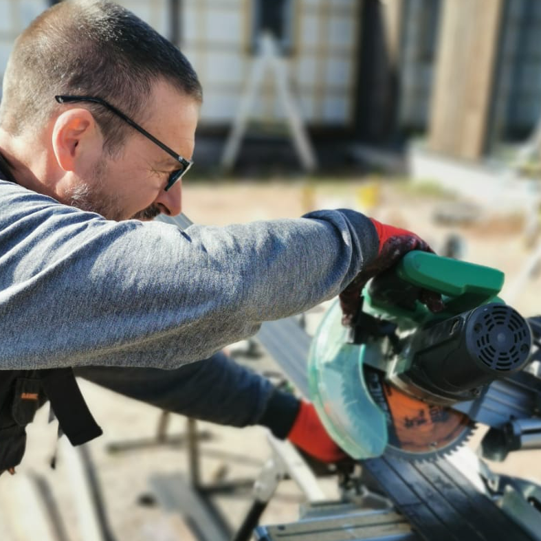 A man is using a circular saw to cut a piece of wood