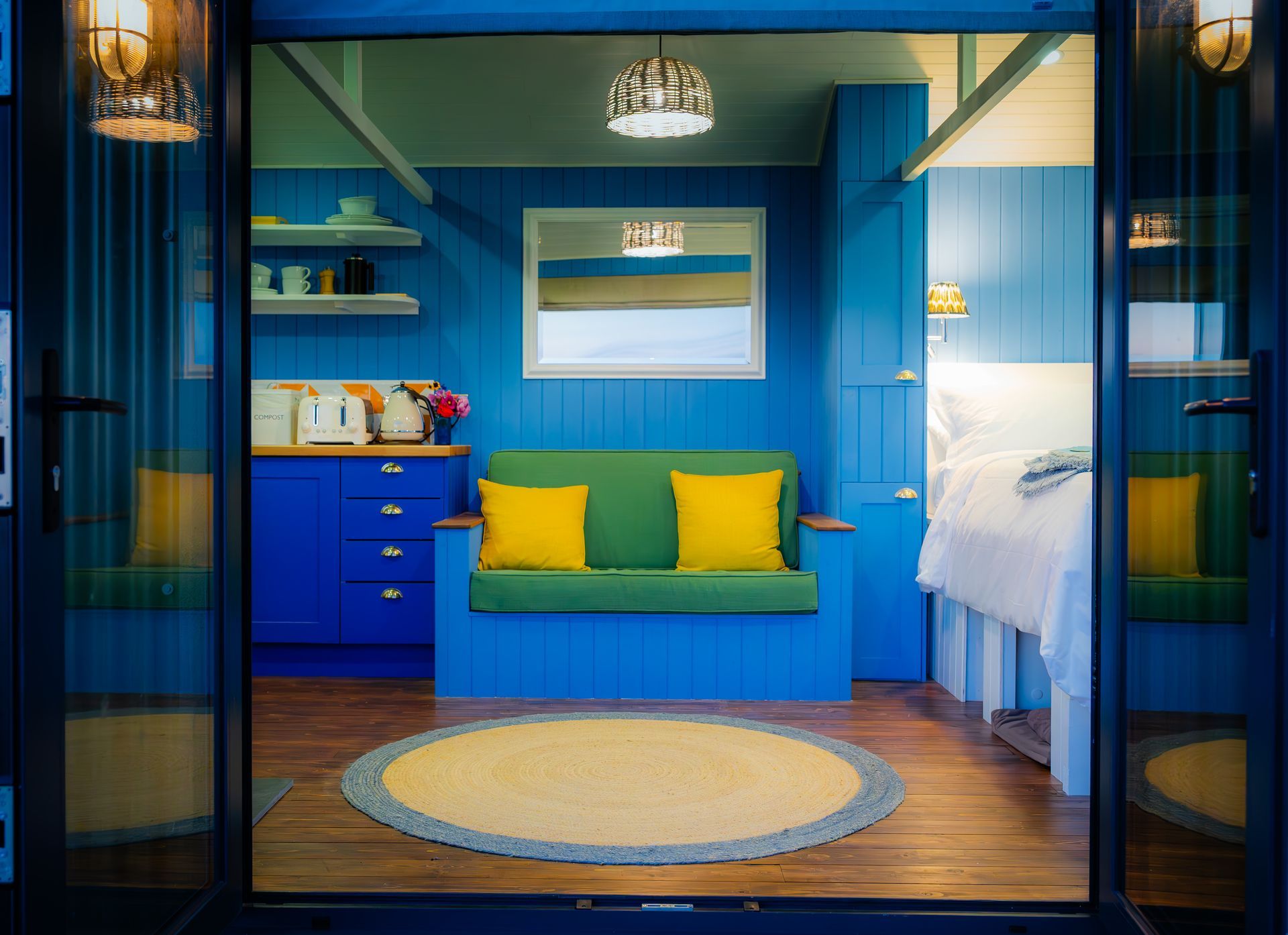 A blue room with a green couch and yellow pillows