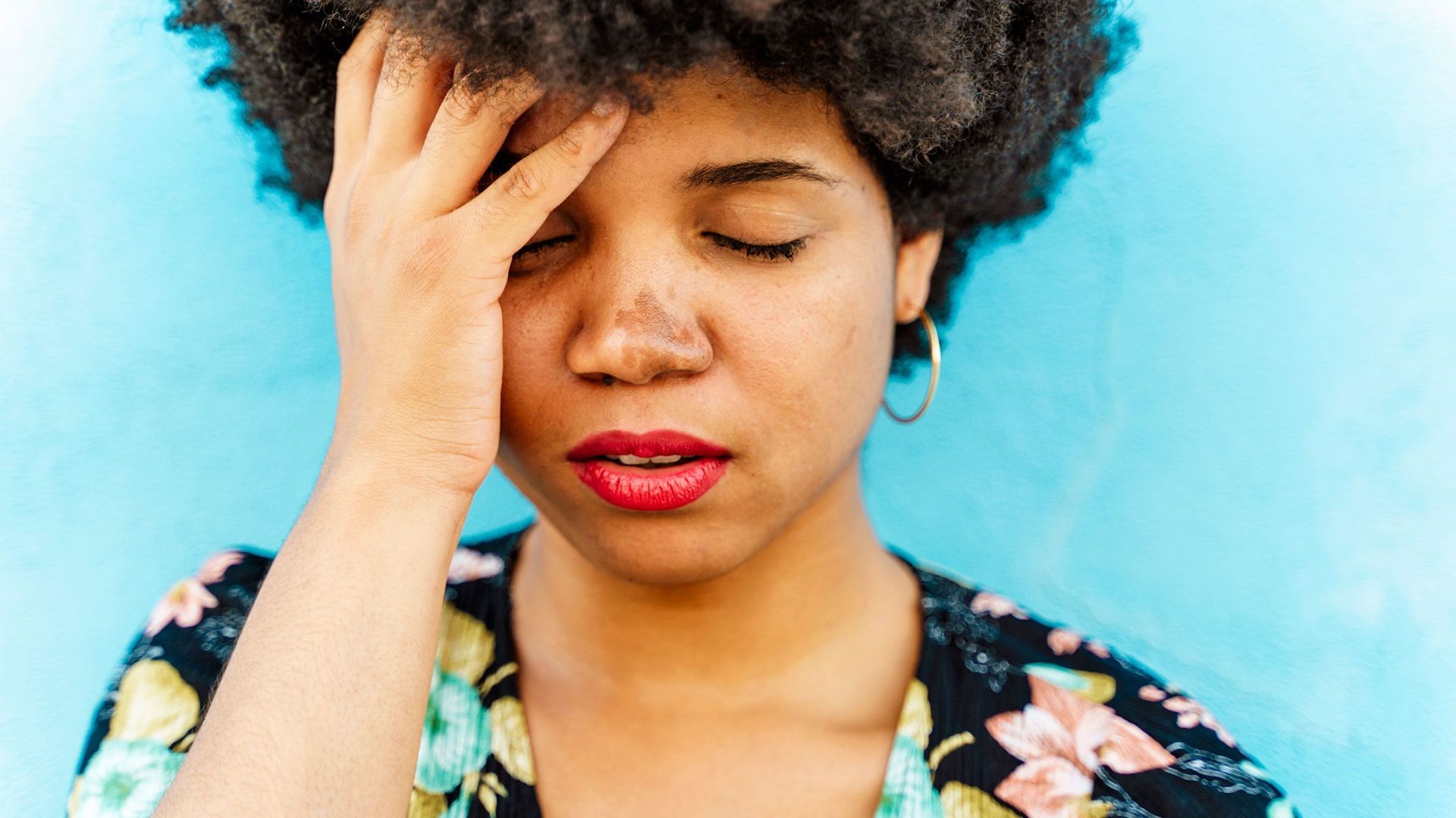 A woman is holding her head with her hand.