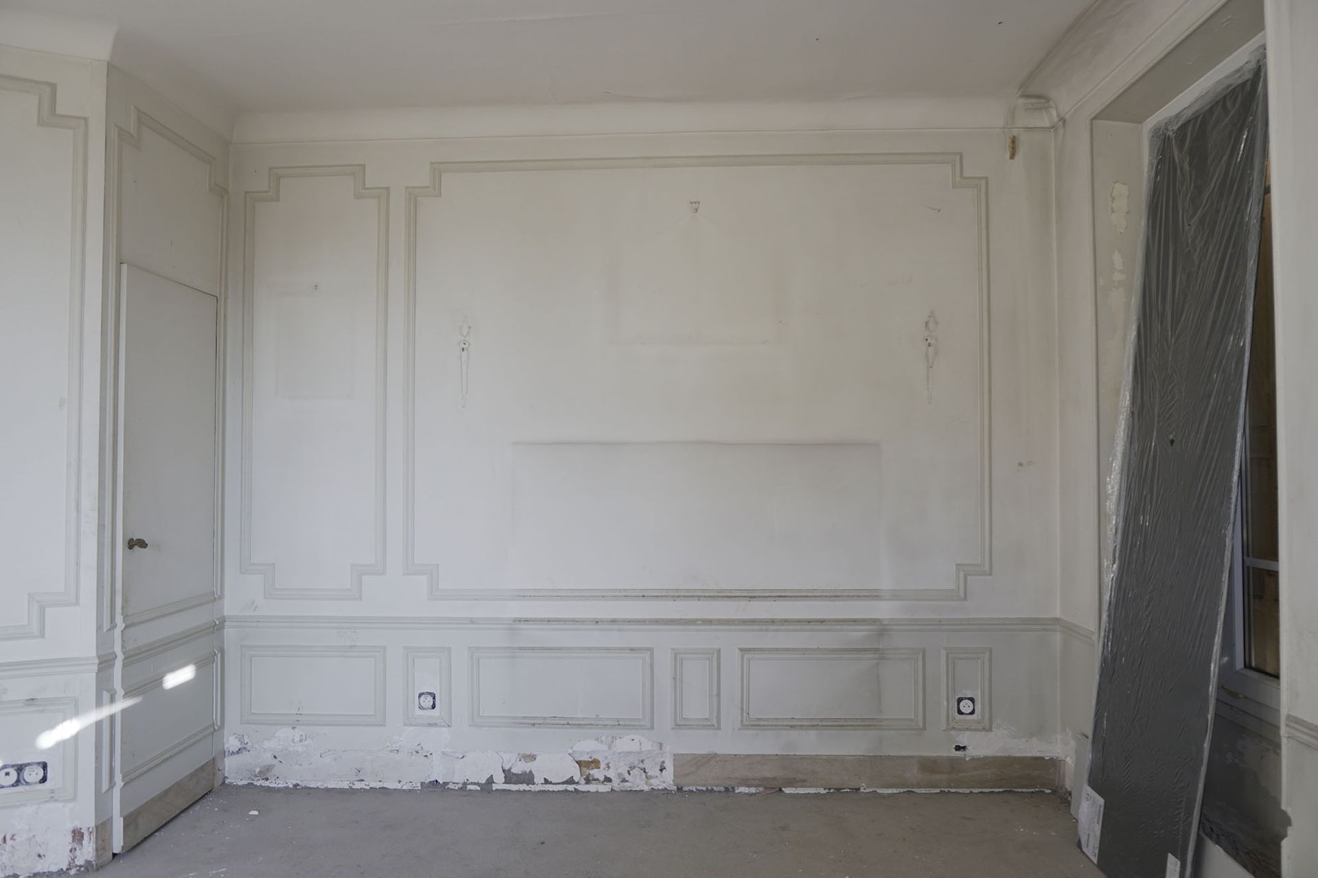 Une pièce vide avec des murs blancs et une porte.