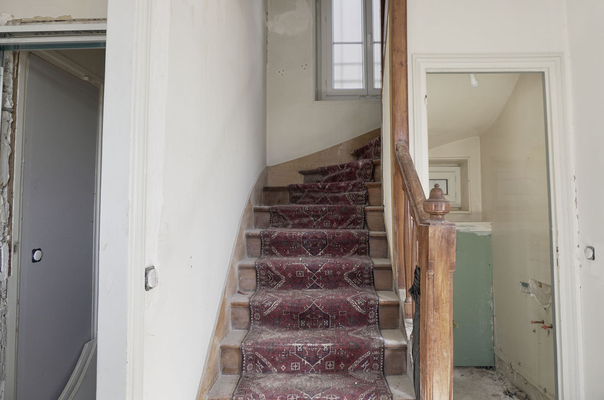 Un escalier avec un tapis rouge menant au deuxième étage d'une maison.