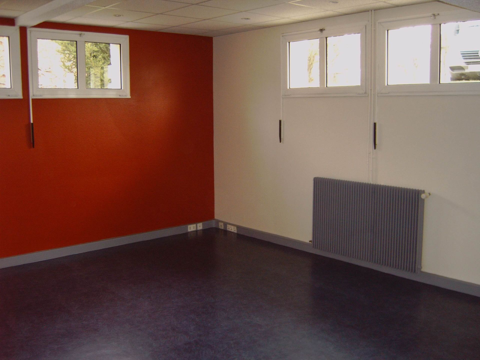 Une pièce vide avec des murs rouges et un radiateur