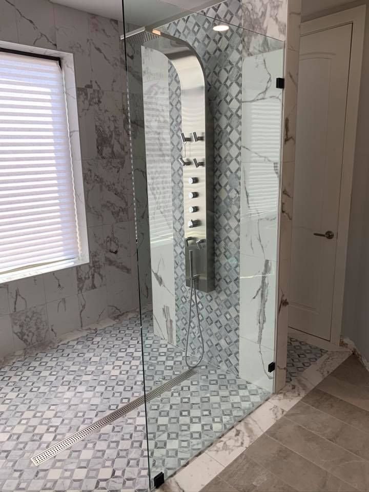 Modern bathroom with marble tiles, a glass shower, and patterned floor.
