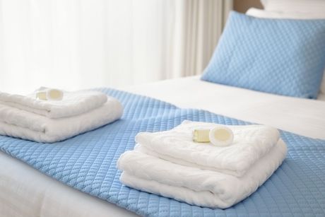 A bed with a blue comforter and white towels on it.