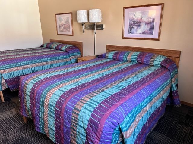 A motel room with two beds and a nightstand.