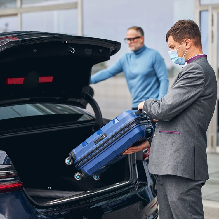 Business traveller with luggage getting into a car