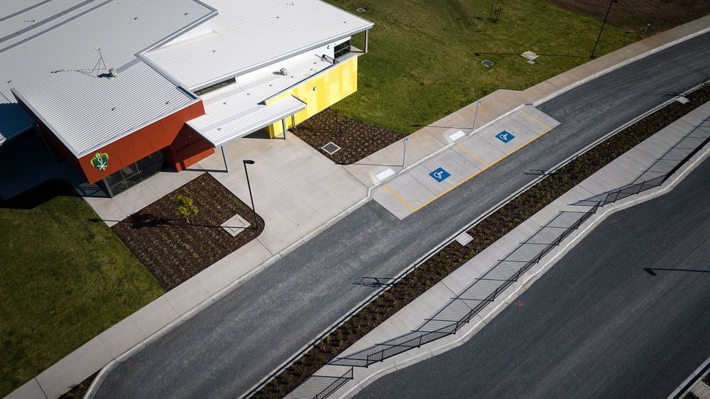 Aerial view of a building with a red and yellow facade, adjacent to a paved road with accessible parking spaces. — Quarrell Civil Construction In Congupna, VIC