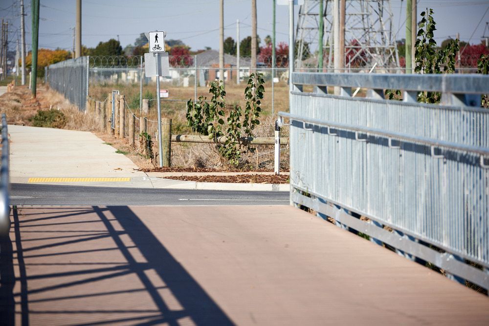 A Paved Pedestrian Bridge With Metal Railings Leads Toward a Sidewalk — Quarrell Civil Construction In Congupna, VIC