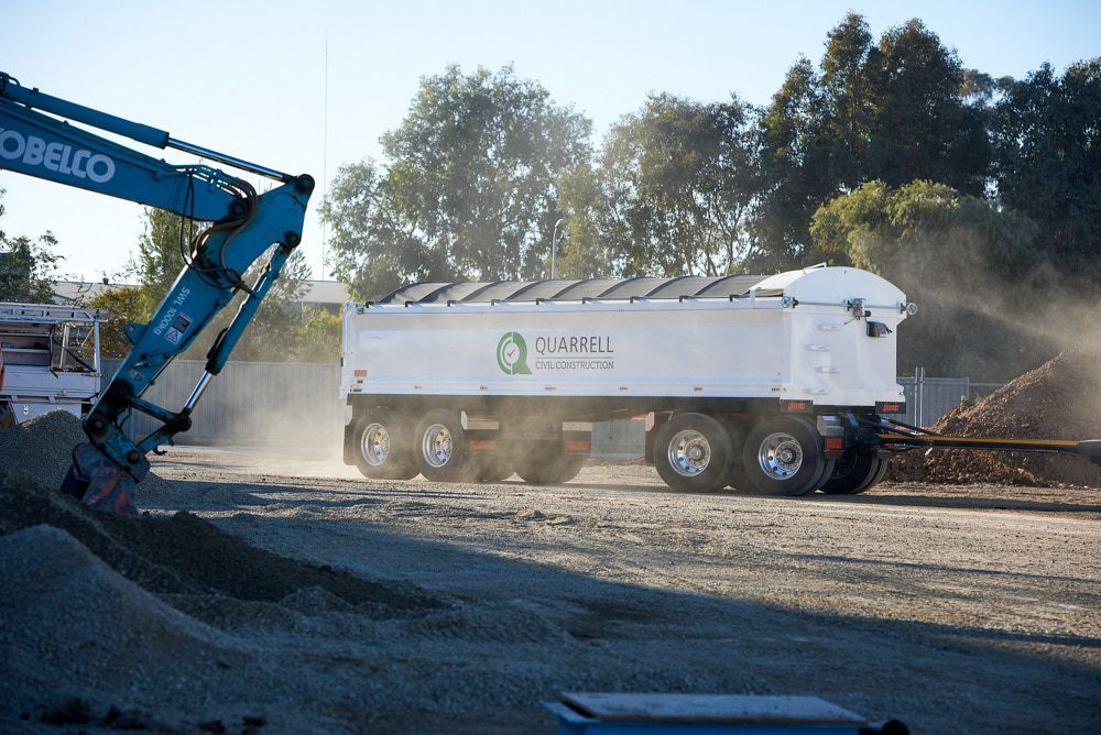 Excavator loading a white semi-trailer with
