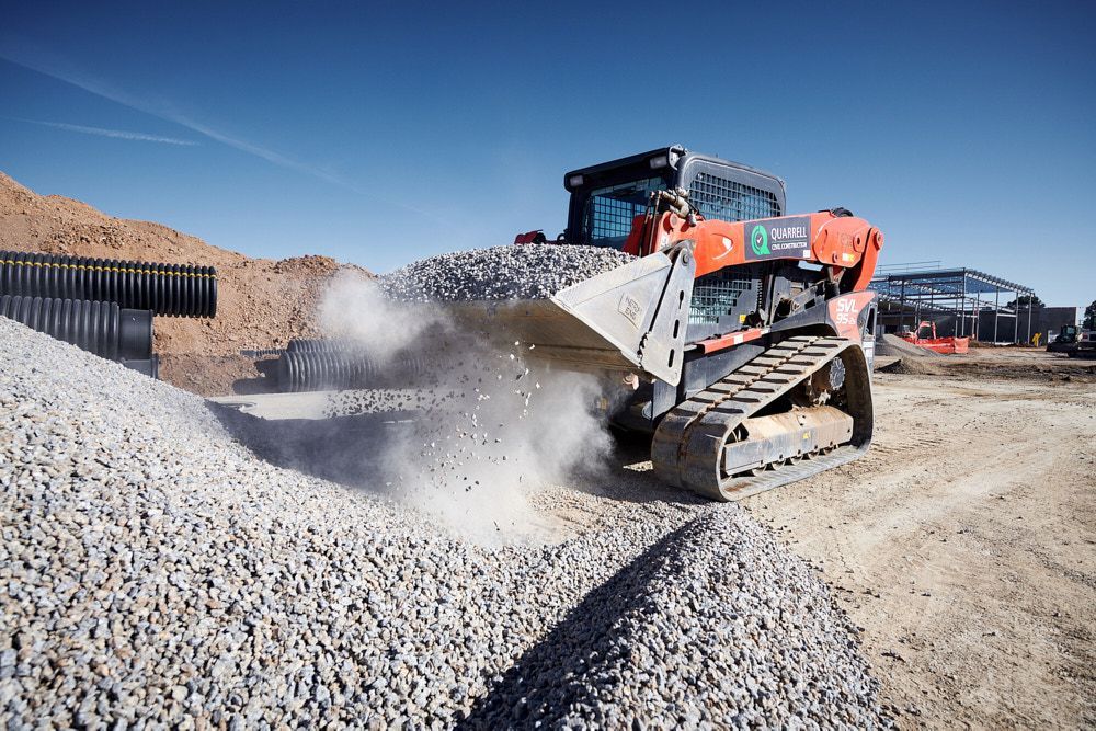 Orange Track Loader Dumping a Bucket of Gravel — Quarrell Civil Construction In Congupna, VIC
