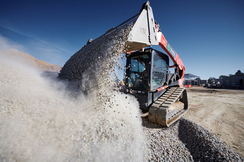 A Track Loader Pours a Bucket of Gravel — Quarrell Civil Construction In Congupna, VIC