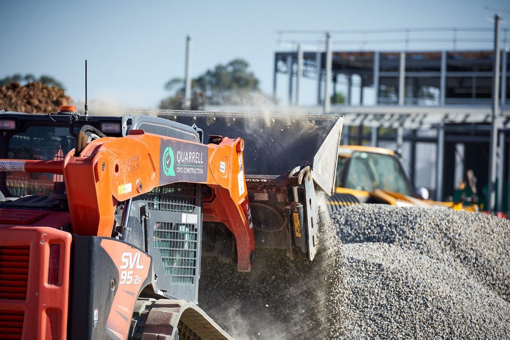An Orange Kubota Svl95 Skid Steer Scoops a Large Pile of Gravel — Quarrell Civil Construction In Congupna, VIC