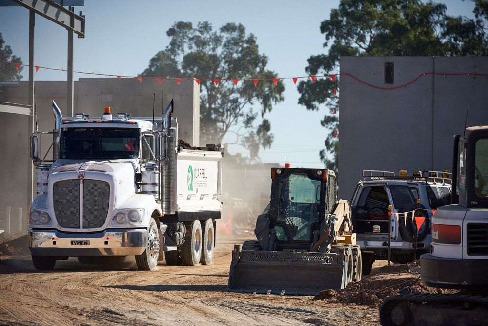 A White Dump Truck and a Small Yellow Loader Operate — Quarrell Civil Construction In Congupna, VIC