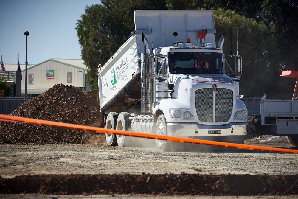 A White Dump Truck Drives Across a Dusty — Quarrell Civil Construction In Congupna, VIC
