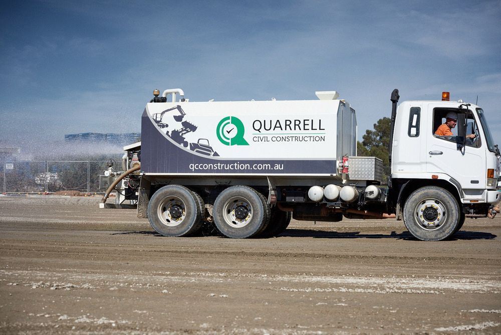 A White Quarrell Civil Construction Water Truck Sprays Water — Quarrell Civil Construction In Congupna, VIC