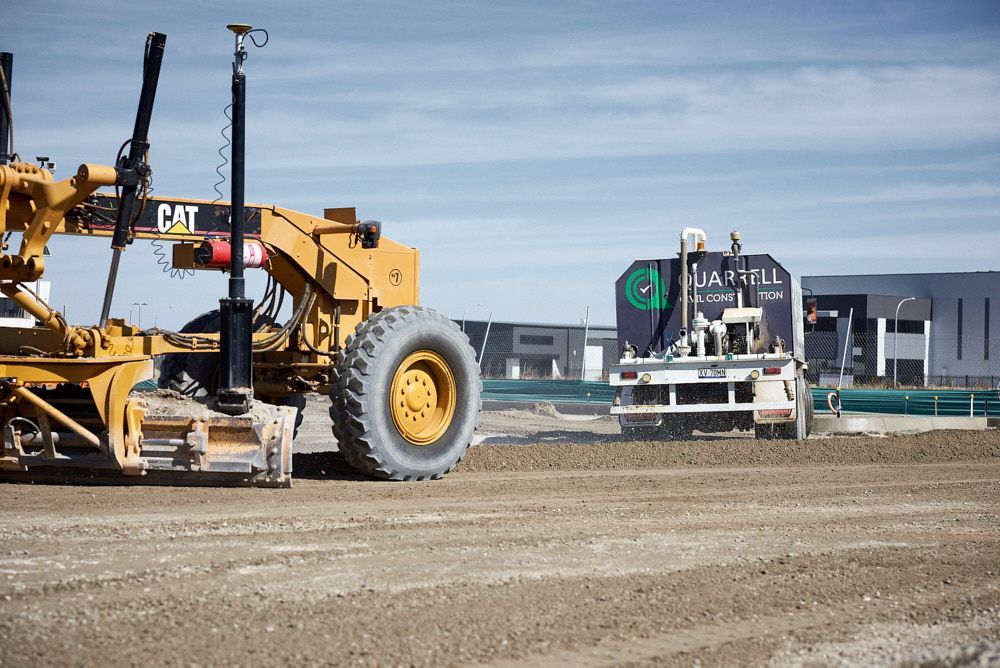 A Yellow Cat Motor Grader Prepares a Dirt Construction Site — Quarrell Civil Construction In Congupna, VIC