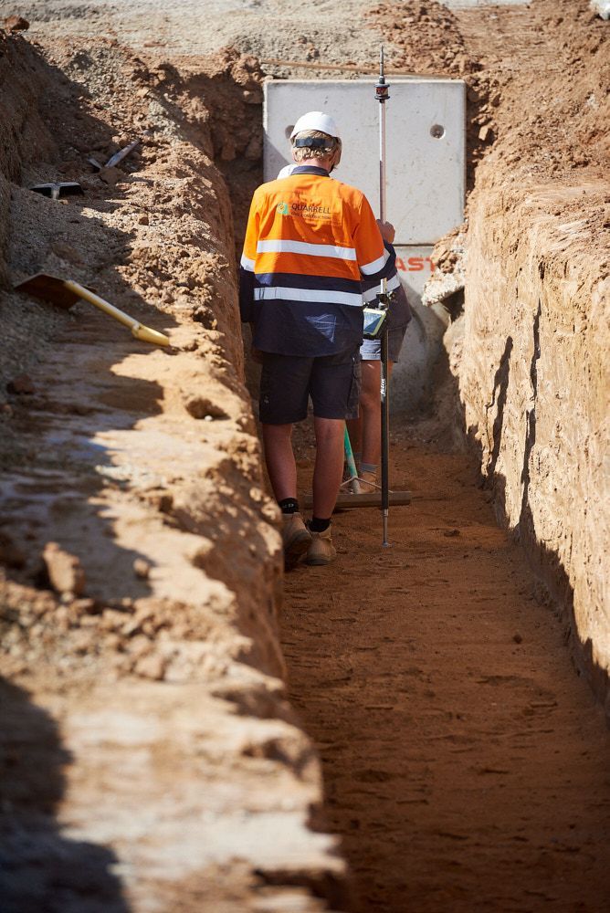 Construction Worker In An Orange Vest Walks Along A Trench — Quarrell Civil Construction In Yarrawonga, VIC