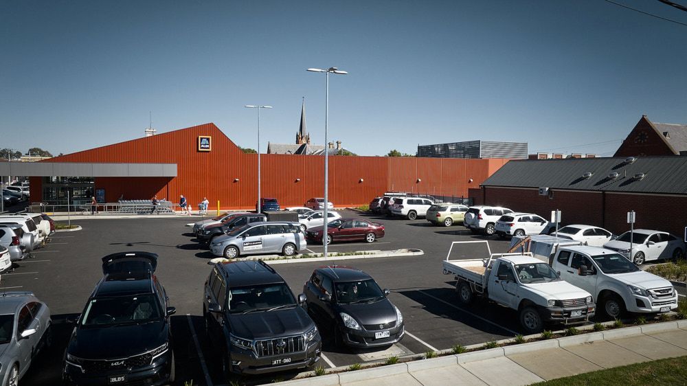 A Sunny Outdoor Parking Lot Featuring a Large Modern Grocery Store — Quarrell Civil Construction In Congupna, VIC