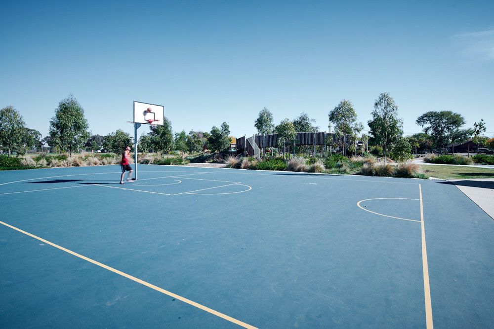 A Person Playing Basketball on an Outdoor Blue Court on a Sunny Day — Quarrell Civil Construction In Congupna, VIC