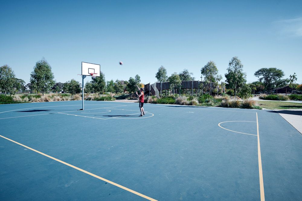 A Person in a Red Shirt Shoots a Basketball Toward a Hoop — Quarrell Civil Construction In Congupna, VIC