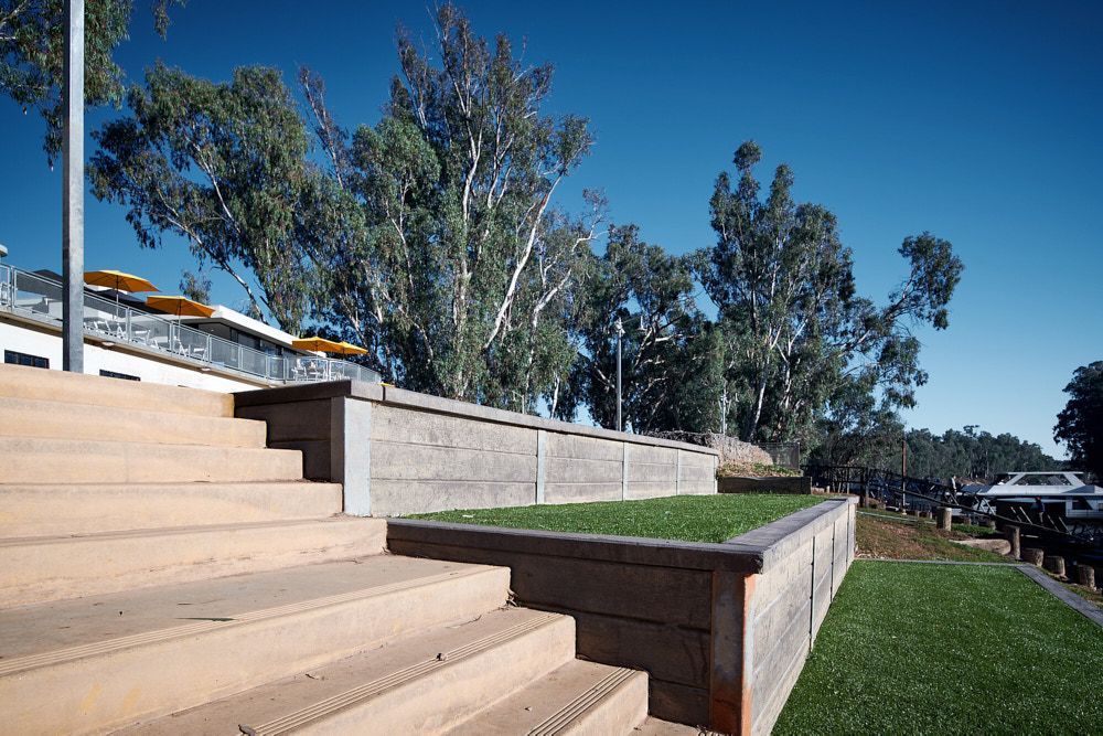 Stairs lead up to a tiered landscape featuring retaining walls and green grass under a clear blue sky — Quarrell Civil Construction In Echuca, VIC