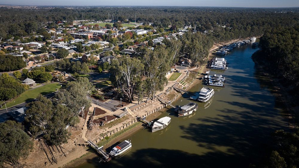 River with docked houseboats, town on the left, trees bordering, sunny day. — Quarrell Civil Construction In Congupna, VIC