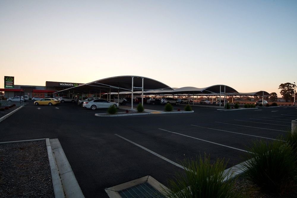 A Parking Lot With Covered Solar Panel Structures Over Several Parked Cars — Quarrell Civil Construction In Congupna, VIC