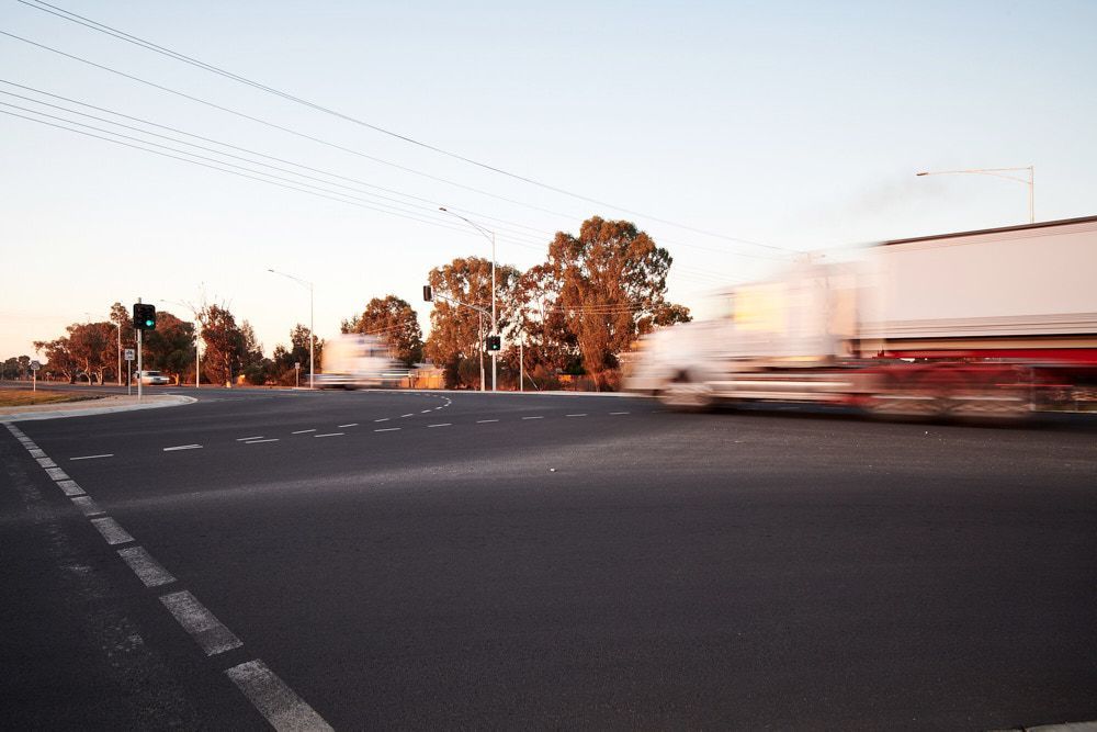 A White Semi-truck Speeds Through an Intersection at Sunset — Quarrell Civil Construction In Congupna, VIC