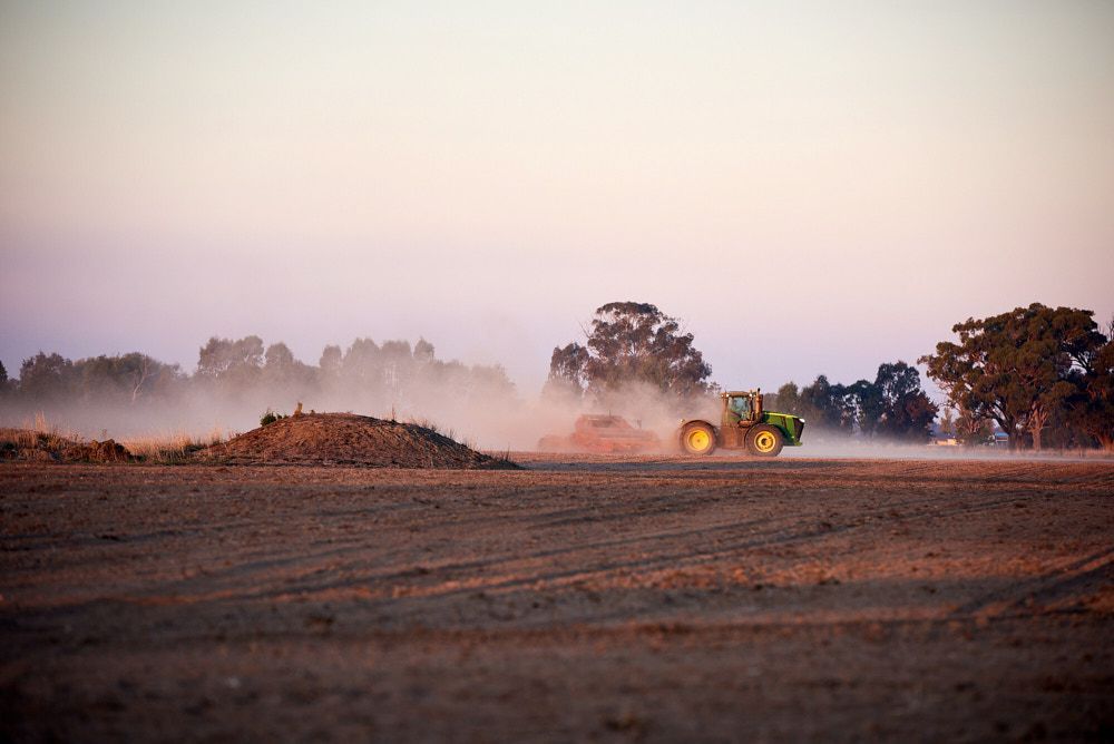 A Green Tractor Plows a Dusty Field Under a Soft — Quarrell Civil Construction In Congupna, VIC