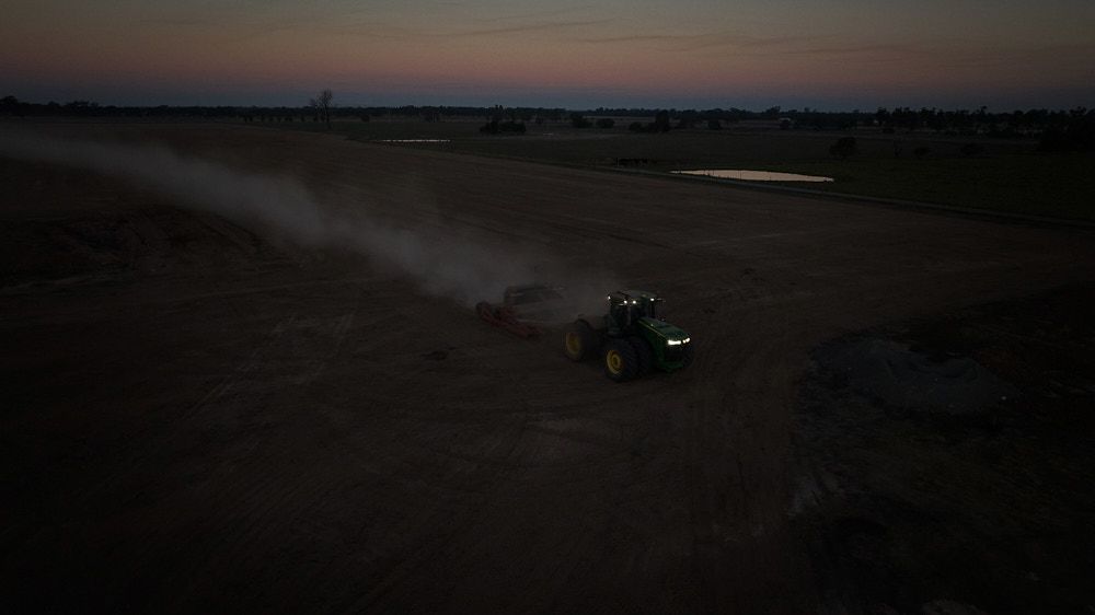 A Green Tractor Plows a Large Field at Twilight — Quarrell Civil Construction In Congupna, VIC