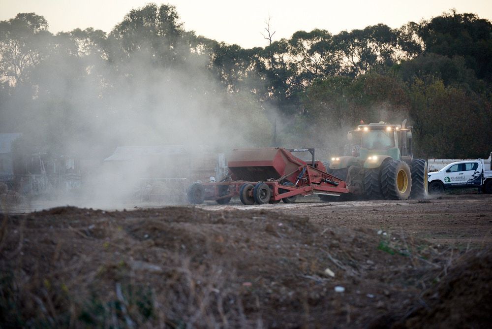 A Green Tractor Pulls a Red Implement Across a Dry — Quarrell Civil Construction In Congupna, VIC