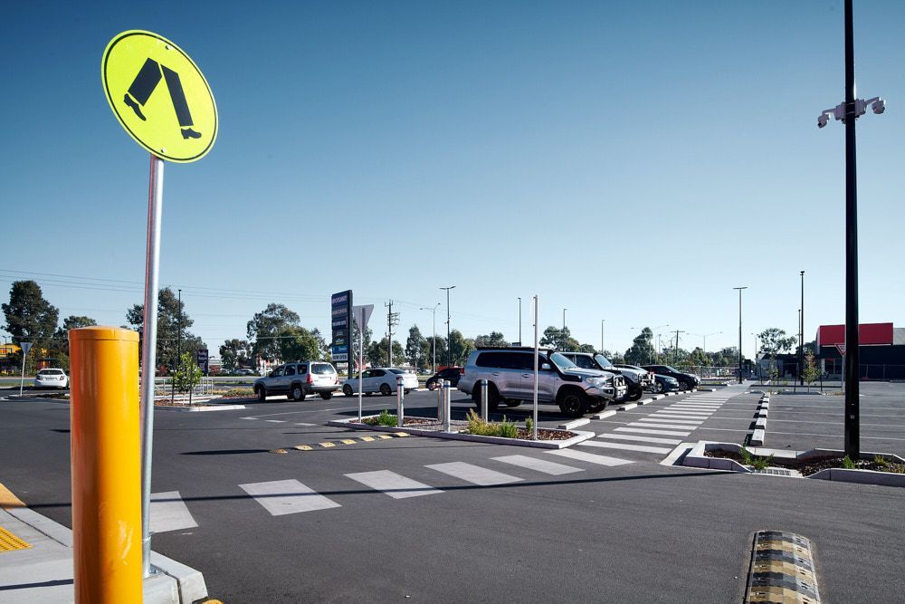 A Pedestrian Crossing Sign Stands in a Sunny Parking Lot — Quarrell Civil Construction In Congupna, VIC