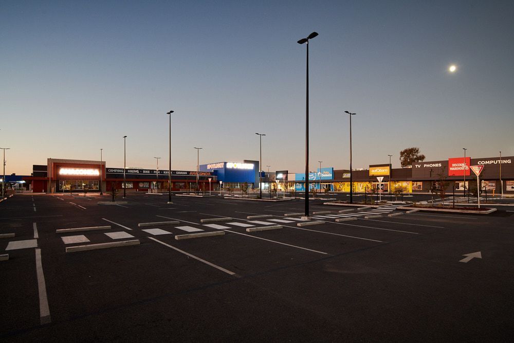 An Empty, Paved Parking Lot in Front of a Strip Mall at Twilight — Quarrell Civil Construction In Congupna, VIC