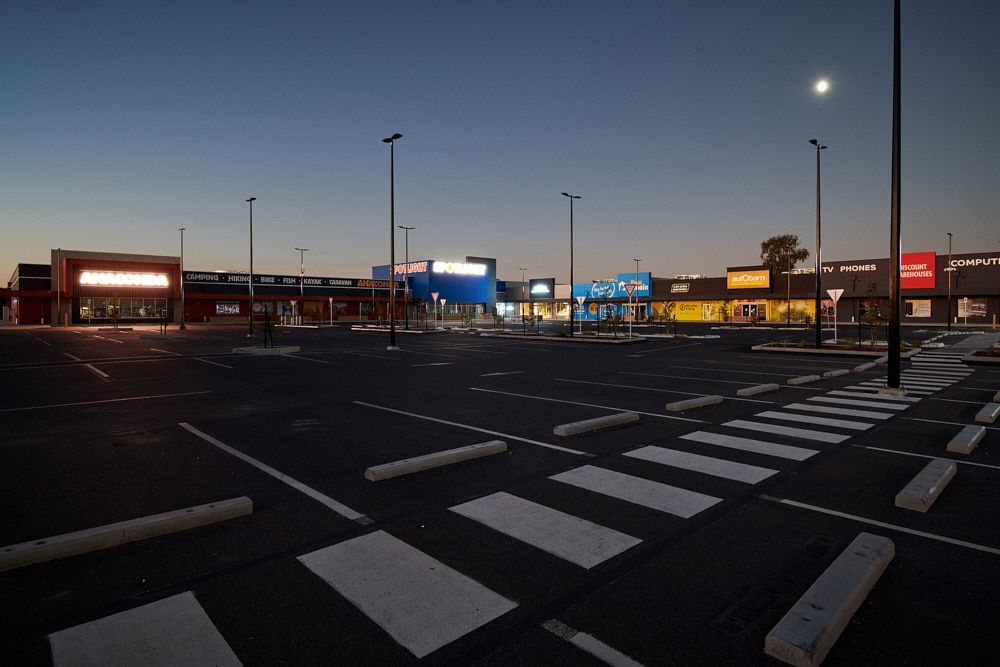 A Dimly Lit Outdoor Shopping Plaza at Dusk With a Large — Quarrell Civil Construction In Congupna, VIC