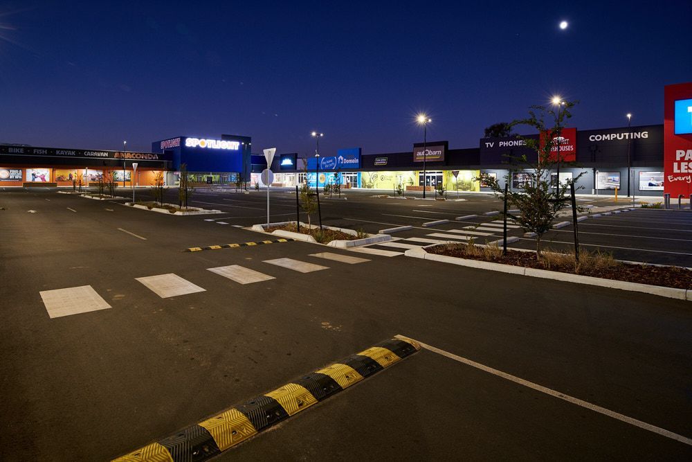 A Quiet, Empty Parking Lot in Front of a Brightly Lit Shopping Center — Quarrell Civil Construction In Congupna, VIC 