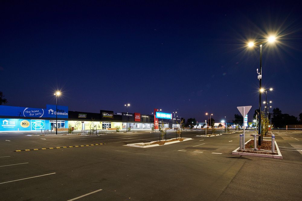 Empty Parking Lot in Front of a Row of Illuminated Retail Stores — Quarrell Civil Construction In Congupna, VIC