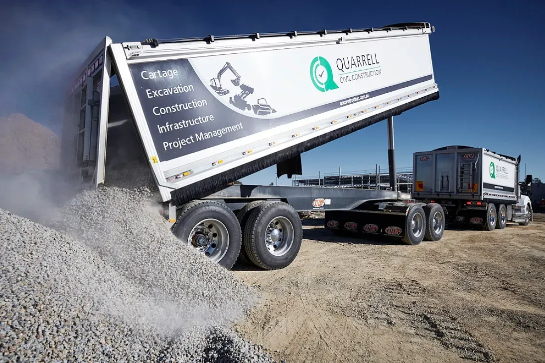 Truck dumping gravel on a dusty surface. White truck bed with company logo tilted high. — Quarrell Civil Construction In Congupna, VIC