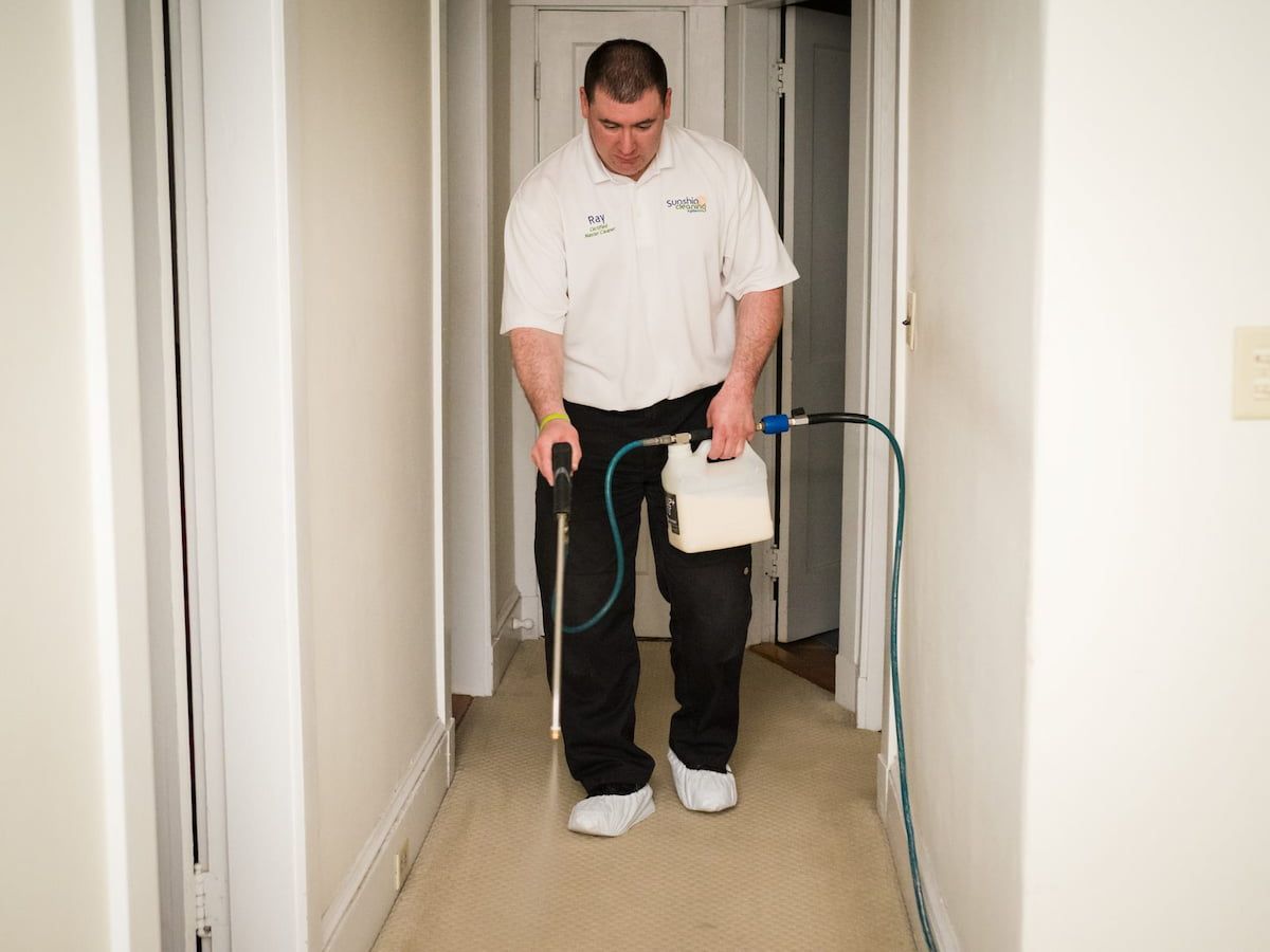 Ray DeMeo applying a pre-treatment to hallway carpet while wearing shoe covers