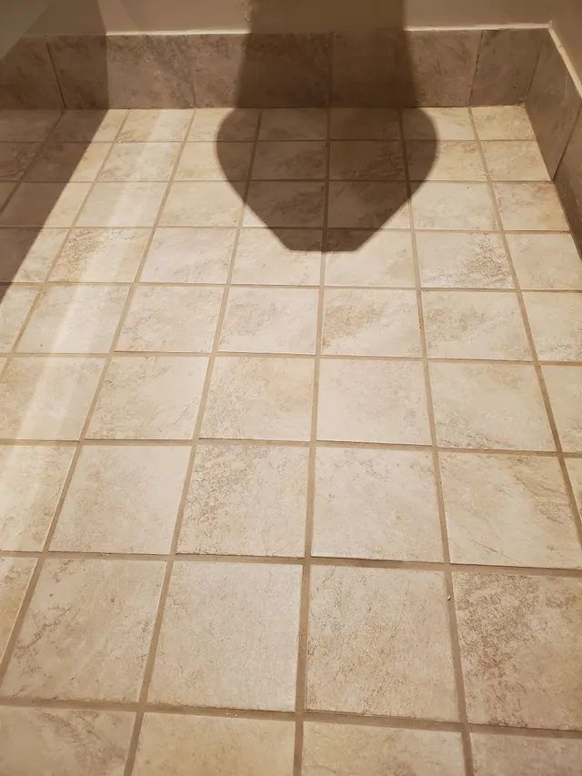 Same office restroom floor after tile and grout cleaning, with grout restored to an even, clean color