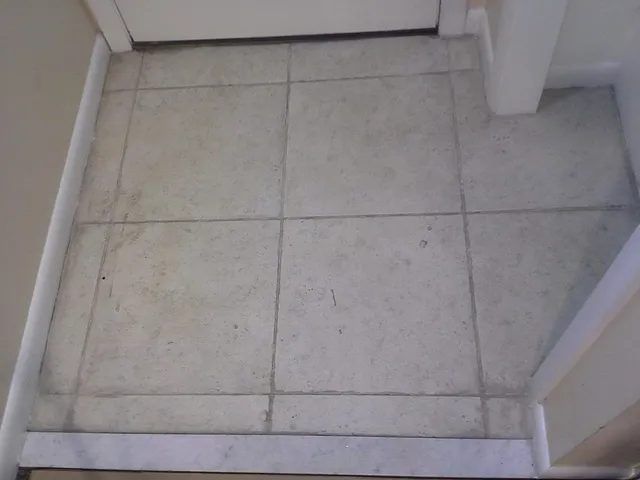 Dingy tile floor and grout at a dental office entrance in Arlington, MA, before cleaning