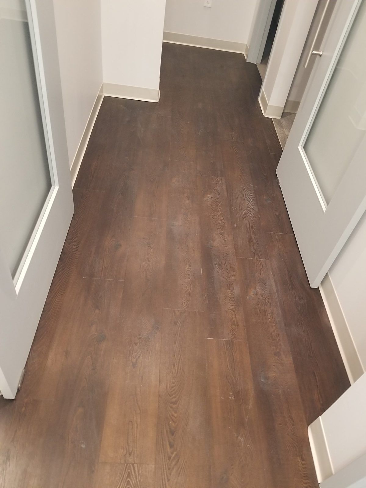Dull, hazy luxury vinyl plank floor in a Waltham, MA dental office, with construction dust trapped under a wax-like coating