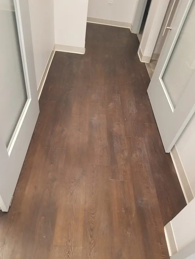 Dull, hazy luxury vinyl plank floor in a Waltham, MA dental office, with construction dust trapped under a wax-like coating